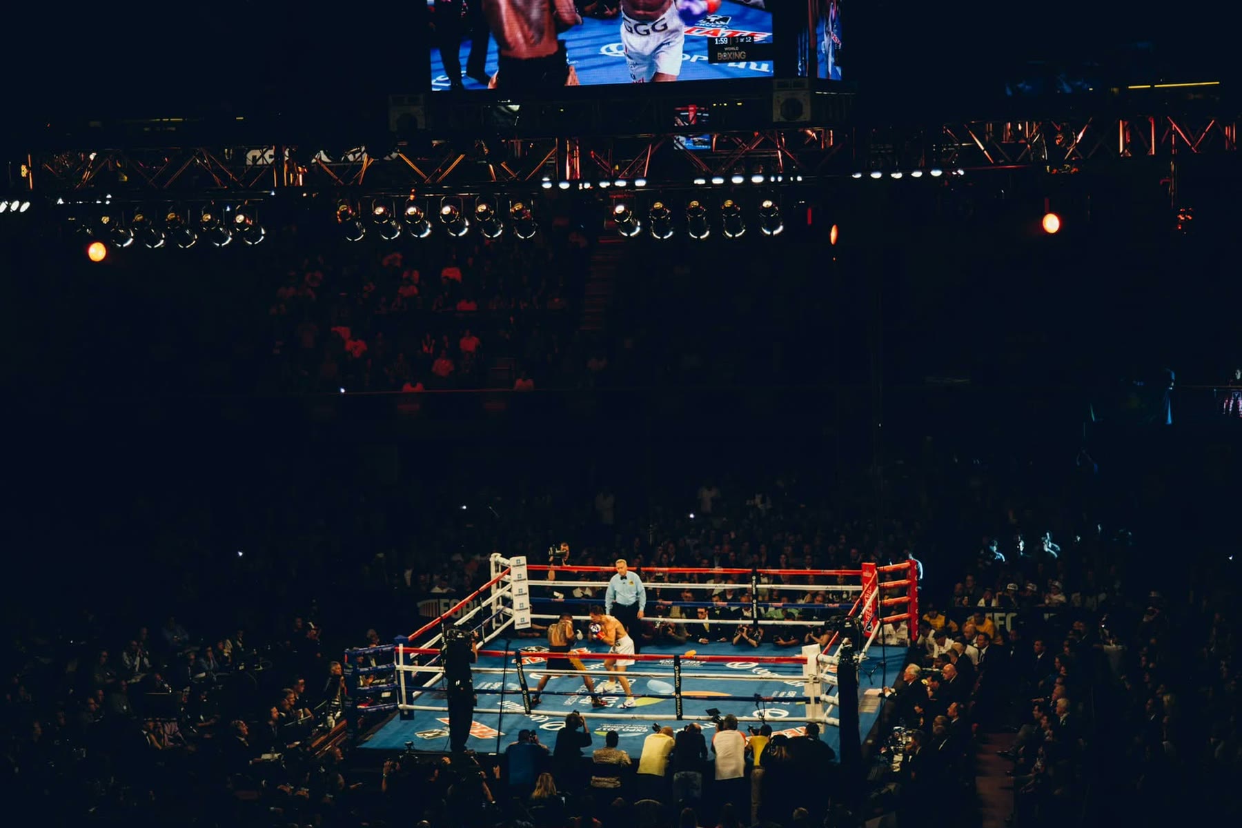 Un ring éclairé au centre d'une salle plongée dans le noir